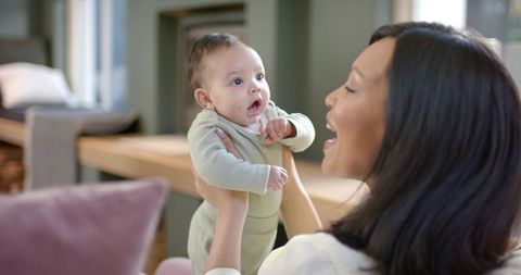 Asian mother engaging infant daughter in warm domestic setting