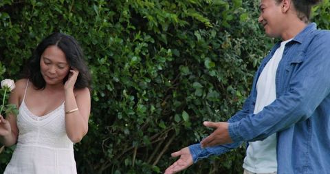 Young Couple Sharing Joyful Outdoor Moment with Flower in Garden Setting