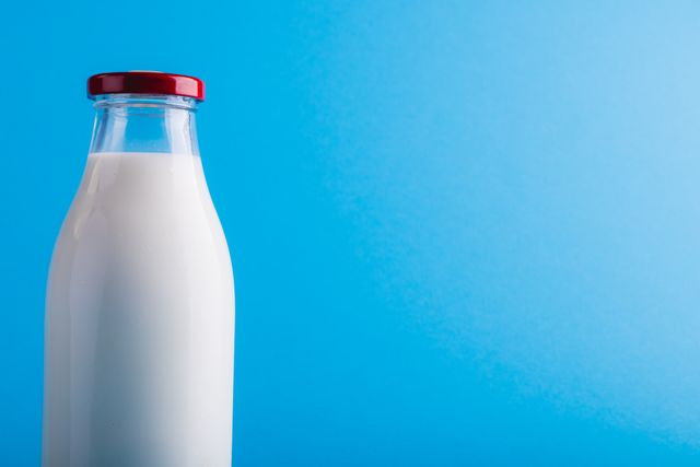 Close-up of milk bottle against blue background with copy space. unaltered, food, drink, studio shot and healthy eating.