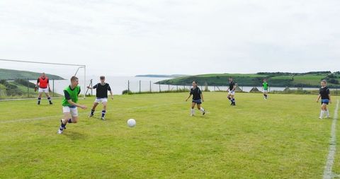 Teen Players Engaging in Soccer Match on Coastal Field