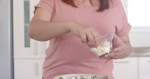 Plus size woman preparing feta cheese vegetable salad