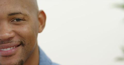 Closeup smiling african man wearing blue shirt showing trimmed beard and eye contact