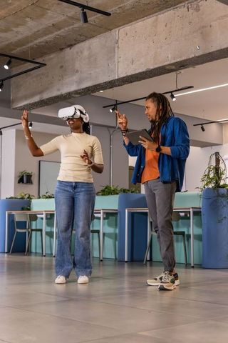 Diverse coworkers testing virtual reality headset while collaborating with tablet in office