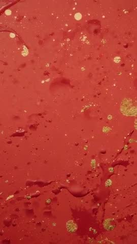 Crimson lacquer flowing with floating gold specks | Macro vertical slow-motion study