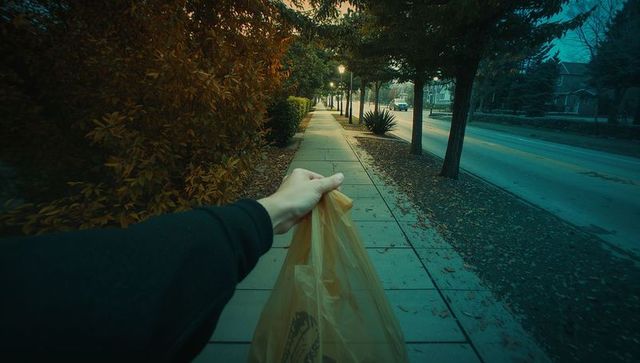 Strolling on sidewalk with plastic grocery bag