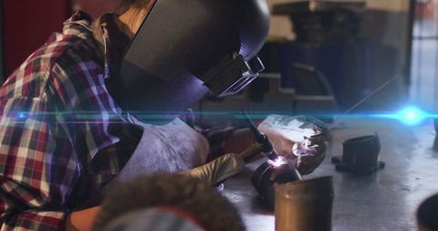 Skilled welder working on metal pipe welding process in industrial workshop