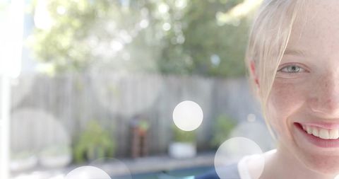 Teenage Girl Smiling in Sunlit Garden with Bokeh Effect
