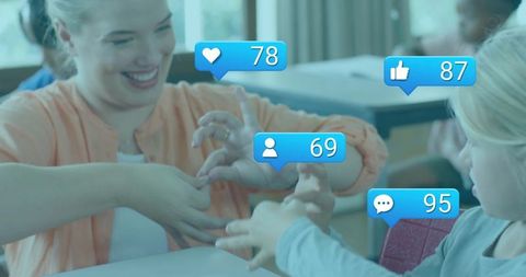 Female teacher playing hand game with children in classroom with social media engagement icons