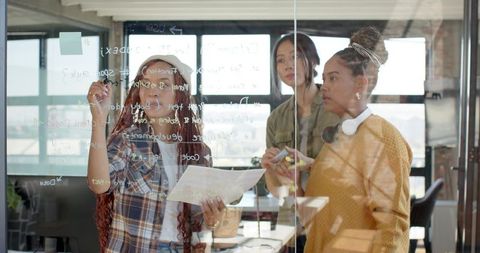 Diverse Team of Women Brainstorming Ideas on Glass Board