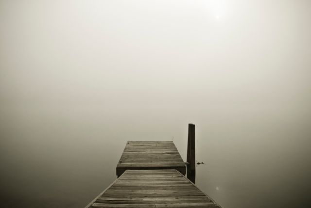 Wooden Pier Extending into Fog over Calm Water at Dusk - Download Free Stock Photos Pikwizard.com