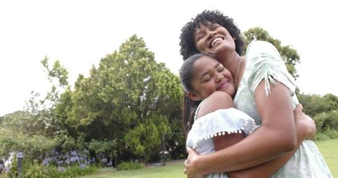 Joyful African American Mother and Daughter Hugging Outdoors