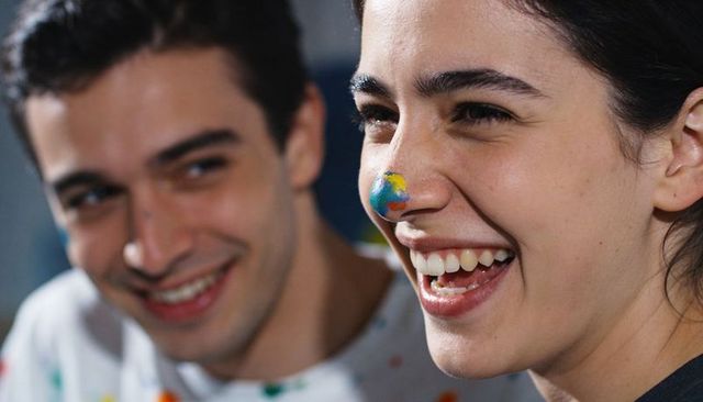 Young friends laughing with globe face paint on nose, colorful paint-spattered portrait