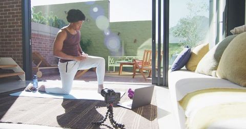 Fit man filming fitness vlog at home in bright living room