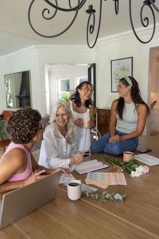 Multigenerational women collaborating on home decor mood board at sunlit kitchen table