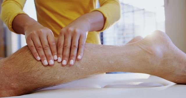 A massage therapist is working on a client's leg, providing a therapeutic touch to alleviate muscle tension, with copy space. The setting suggests a focus on wellness and physical therapy, emphasizing the importance of professional care in maintaining bodily health.