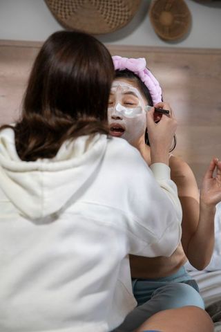 Two women friends enjoy facial treatment at home in cozy setting