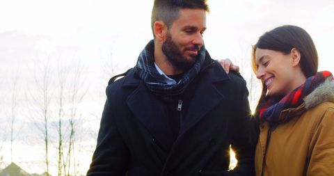 Couple smiling while charging electric car on winter day