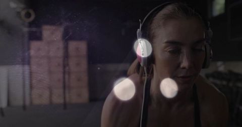 Focused Female Athlete Training with Over-Ear Headphones in Dim Gym, Moody Workout Mood