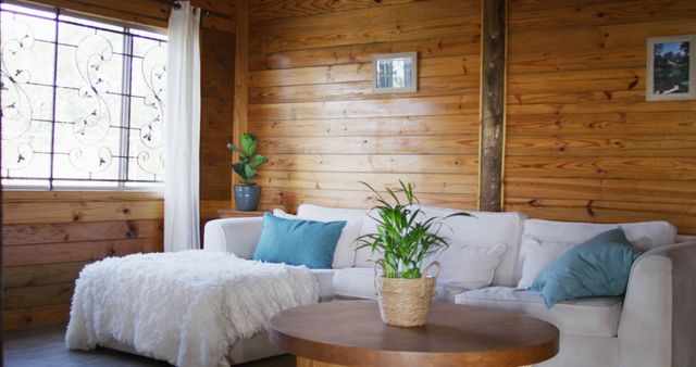 Cozy living room featuring wooden walls and a white sofa, complemented by indoor plants and natural light. Ideal for articles or websites related to home decor, rustic style interiors, modern living spaces, or relaxation environments.