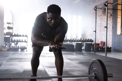 African american man preparing barbell lift with chalk in industrial warehouse gym