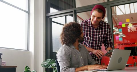 Creative Colleagues Collaborating with Laptop and Tablet in Modern Office