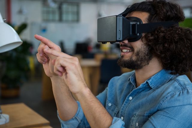 Graphic designer using virtual reality headset in a modern office. Ideal for depicting innovative technology in creative work environments, showcasing modern office setups, or illustrating the use of VR in digital design and creative industries.