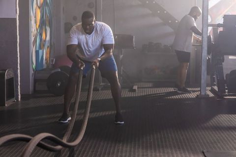 African man training with battle ropes in industrial gym strength and conditioning workout
