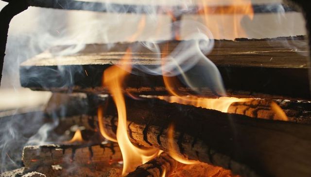 Crackling fireplace with burning logs, dancing flames and smoky embers for cozy hearth