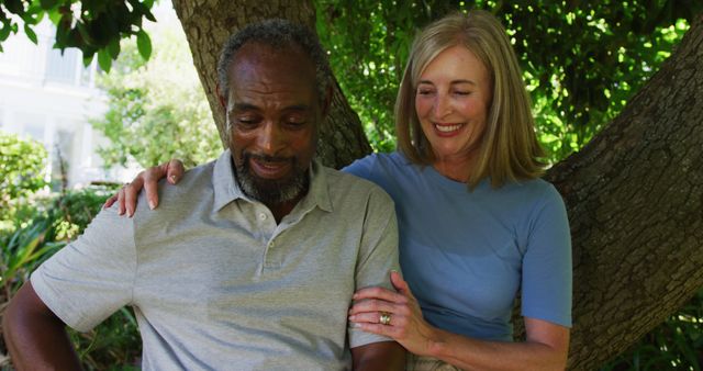 Diverse senior couple in garden taking selfie sitting under a tree and smiling - Download Free Stock Photos Pikwizard.com