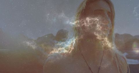 Mystical long-haired man embracing celestial swirl by coastline