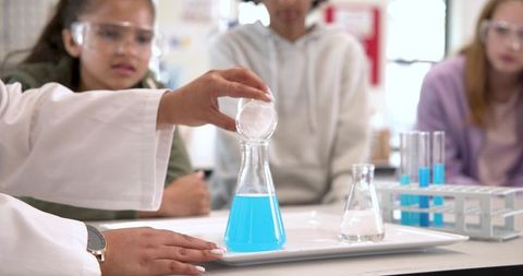 Science Teacher and Students Engaged in Chemistry Experiment with Blue Liquid