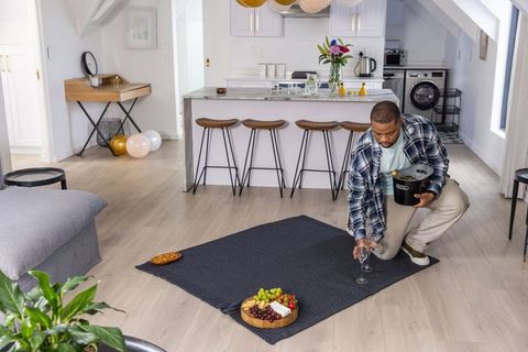 African american man placing wine glass from ice bucket for cozy indoor picnic in kitchen