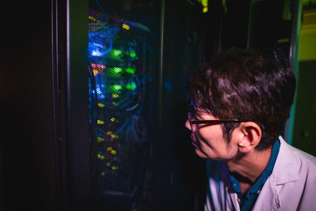 Asian male technician is examining servers in data center. technology, cloud computing, communication and networking.