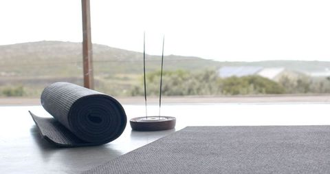 Peaceful Home Yoga Setup with Rolled Mat and Incense