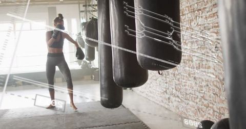 Woman energetically training with heavy boxing bags in urban gym