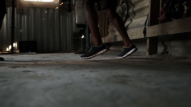 Low section showing an athlete in motion while training punches in a rustic gym. His legs and sports shoes indicate high-energy activity and focus on fitness. This visual can be useful for promoting gym services, showcasing fitness routines, or inspiring workout culture.