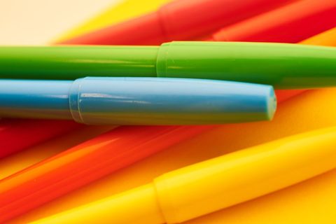 Colorful pens arranged on yellow background