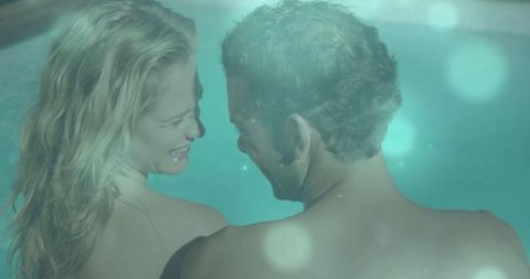 Couple Relaxing in Pool with Lens Flare Highlighting Intimate Moments