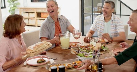 Friends Enjoying Lively Mealtime Gathering with Laughter and Food