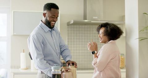Couple preparing breakfast and enjoying morning coffee at sunlit kitchen counter
