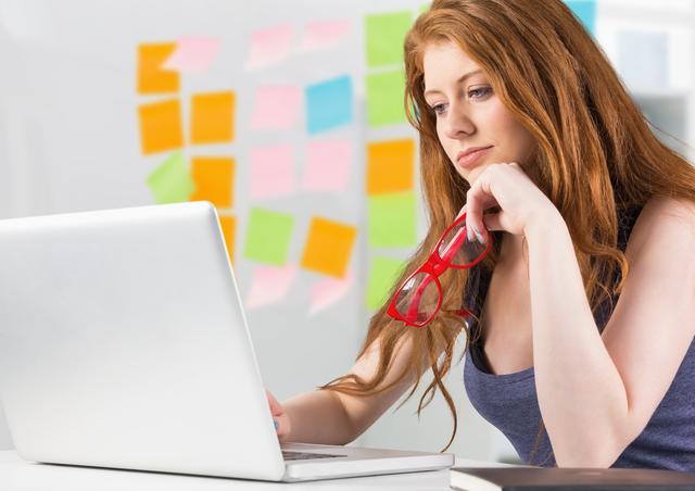 Digital composition of woman using laptop against sticky notes in background