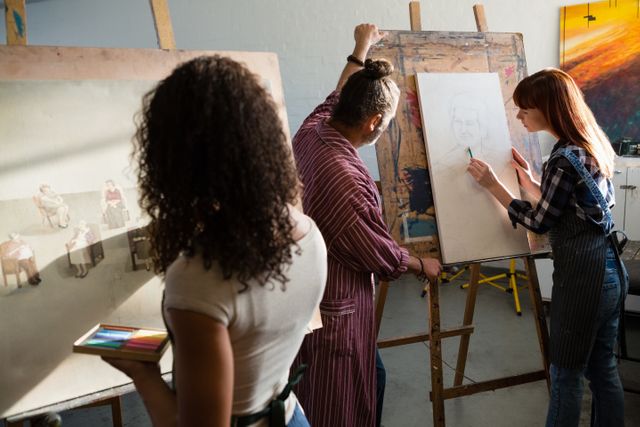 Art students painting on canvas in a classroom setting with a teacher assisting. Ideal for use in educational materials, art school promotions, creativity workshops, and artistic community events.