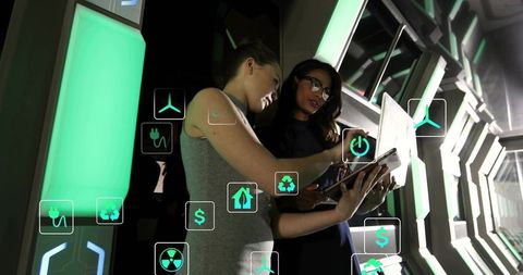 Women collaborating with tablet in green futuristic corridor displaying ar analytics icons