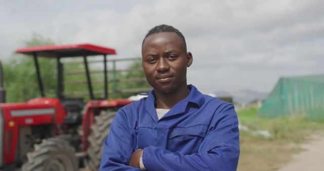 Confident African American Farmer in Blue Overalls Standing in Front of Tractor - Download Free Stock Images Pikwizard.com