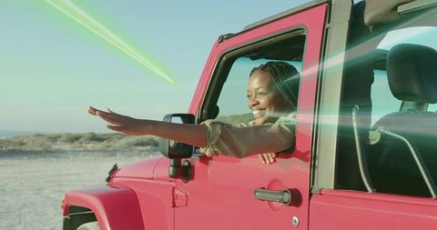 Optimistic woman enjoying coastal road trip in open-top red jeep