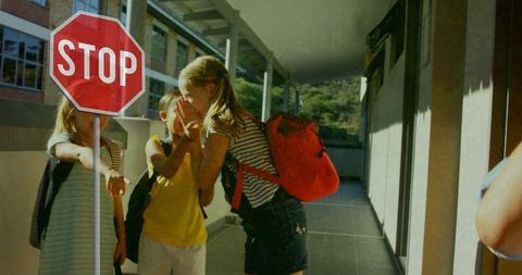Playful Schoolchildren Laughing Near Stop Sign During Recess