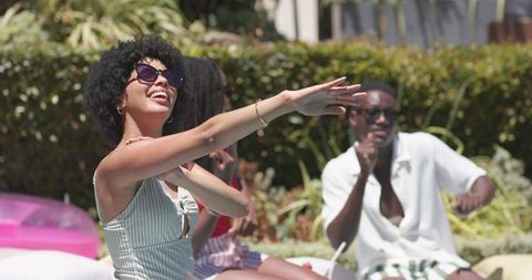 Sunlit poolside friends laughing and relaxing together, african american adults enjoying summer