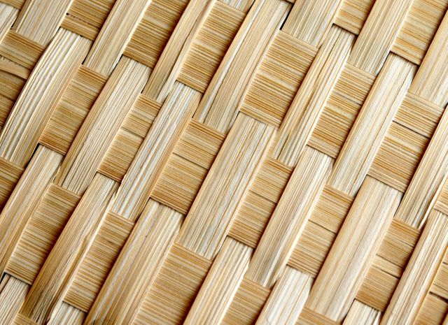 Detailed close-up, highlighting intricate weaving pattern in natural straw fibers. Useful for design backgrounds, promotional materials for eco-friendly products, or traditional crafts showcases. Perfect for blogs, websites, or packaging designs emphasizing natural or handmade themes.