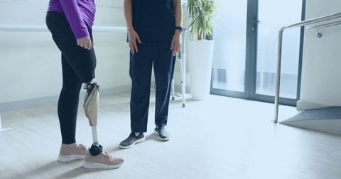 Woman With Prosthetic Leg Practicing in Rehab Room