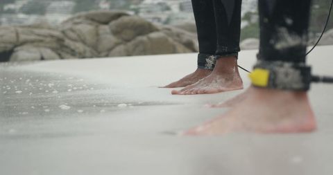 Surfers' Feet on Sandy Beach Preparing to Ride Waves